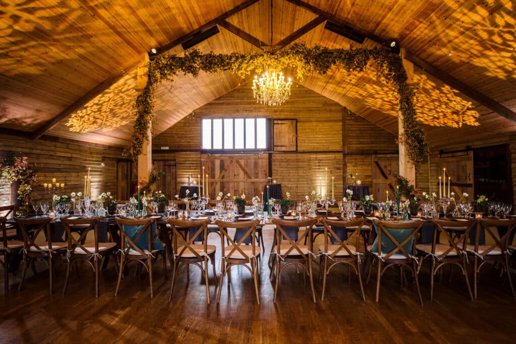 Rustic Surrey barn wedding venue with chandeliers and wooden chairs at High Billinghurst Farm.