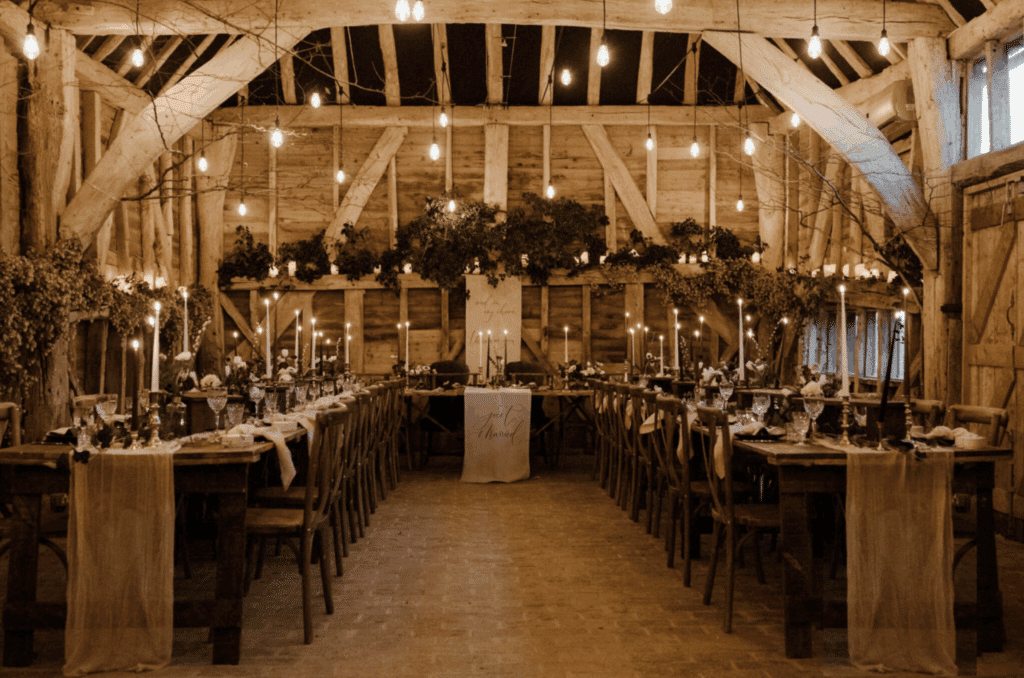 Rustic barn wedding reception with long banquet tables and fairy lights at High Billinghurst Farm.