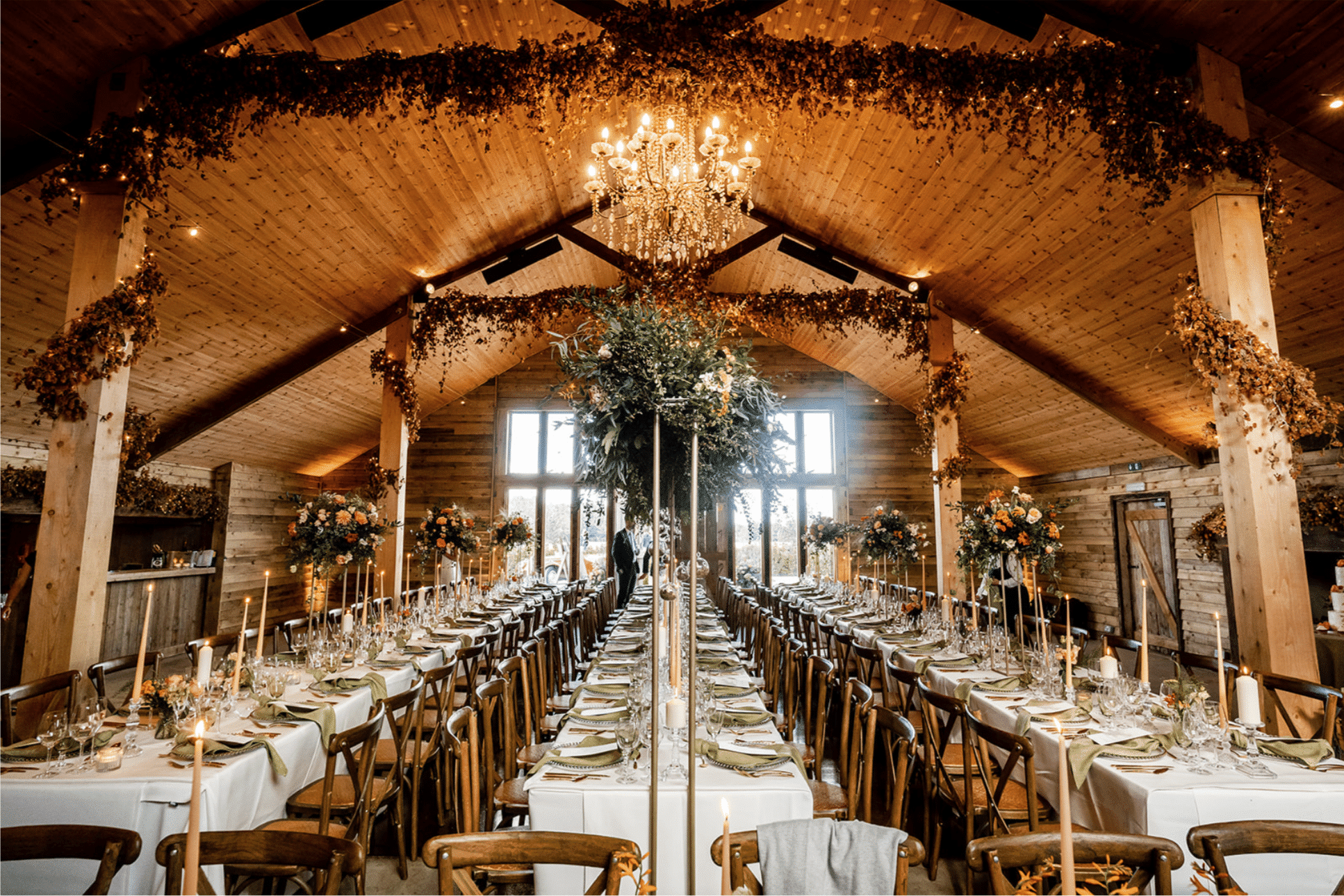 Rustic Surrey barn wedding venue decorated with fairy lights, chandeliers, and long banquet tables at High Billinghurst Farm