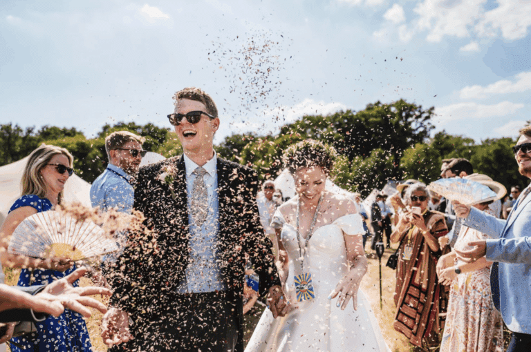 Bride and groom walking through confetti at High Billinghurst Farm outdoor wedding