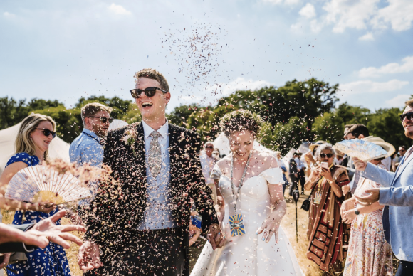 Bride and groom walking through confetti at High Billinghurst Farm outdoor wedding